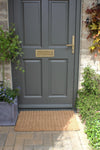 Atlantic Mats Chedworth coir doormat in front of a grey front door