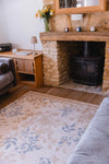 Atlantic Mats Recycled Rug in Gold Rose design in a cozy living room with a stone fireplace
