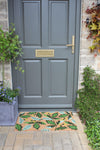Atlantic Mats RHS Bloom Coir Collection Autumn Oak doormat in front of a grey door