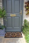 Atlantic Mats RHS Bloom Coir Gertrude Jekyll Tile doormat in front of a grey door
