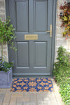 Atlantic Mats RHS Bloom Coir Collection Jekyll Floral doormat in front of a grey door