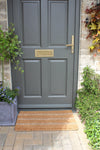 Atlantic Mats Tetbury striped seagrass and coir doormat in front of a grey door