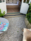Extra large rope doormat by Atlantic Mats at the entrance of a garden room with gravel flooring.