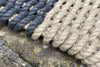 Close-up of a grey and natural stripe rope outdoor doormat by Atlantic Mats on stone.