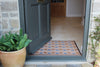 Atlantic Mats Zig-zag Paws Ocean Mat with blue paw prints at an open grey front door